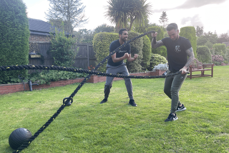 Sam coaching a client with battle ropes